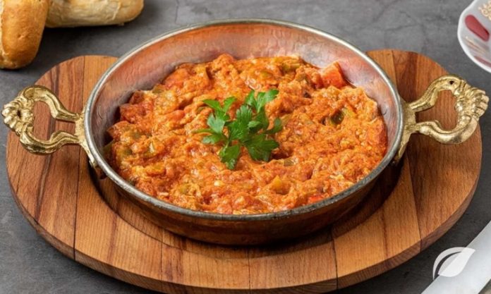 Menemen Tartışmaları Türk Mutfağında Bitmeyen Lezzet Çekişmesi Türk mutfağının en sevilen kahvaltı yemeklerinden biri olan menemen, yıllardır süren büyük bir tartışmanın da merkezinde yer alıyor. Asırlardır sofralarda yer bulan bu lezzet, basit malzemelerle hazırlanmasına rağmen, “Soğansız mı olur yoksa soğanlı mı olmalı?” sorusu etrafında hararetli tartışmalara neden oluyor. Konulu bir haber görseli.
