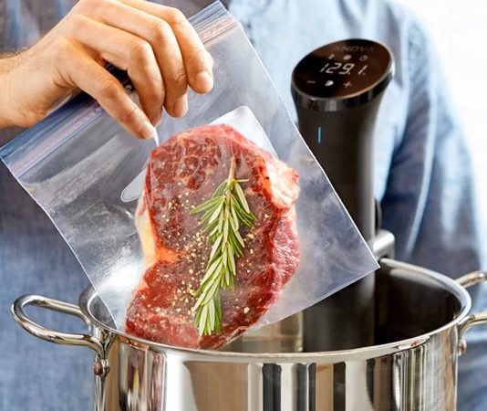 Sous Vide Yöntemiyle Yemeklerde Mükemmel Lezzet Sous vide Fransızca’da “vakum altında” anlamına gelen bir pişirme tekniğidir. Yiyecekler özel poşetlerin içine yerleştirilip vakumlanır ve ardından kontrollü bir şekilde düşük sıcaklıkta su banyosunda pişirilir. Bu yöntem 1970’li yıllarda profesyonel şefler tarafından keşfedilmiş ve zamanla restoran mutfaklarından ev mutfaklarına kadar yayılmıştır. Özellikle et, balık ve sebzelerde istenen pişirme derecesine ulaşmayı kolaylaştırdığı için tercih edilmektedir. Konulu bir haber görseli.