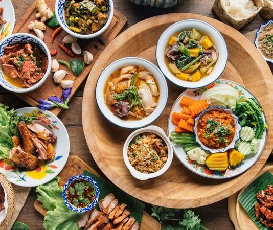 Tayland mutfağı, dünyanın dört bir yanında egzotik lezzetleri, dengeli tatları ve eşsiz baharat kullanımıyla tanınır. Tatlı, ekşi, tuzlu ve acı tatların aynı tabakta ustaca harmanlanması, bu mutfağı gastronomi dünyasında özel bir yere taşır. Uzak Doğu’nun mutfak kültürleri arasında Tayland yemekleri, hem sağlıklı hem de doyurucu oluşuyla öne çıkar. Sokak lezzetlerinden lüks restoran menülerine kadar uzanan geniş yelpazesi sayesinde her damak tadına uygun alternatifler sunar. Konulu bir haber görseli.