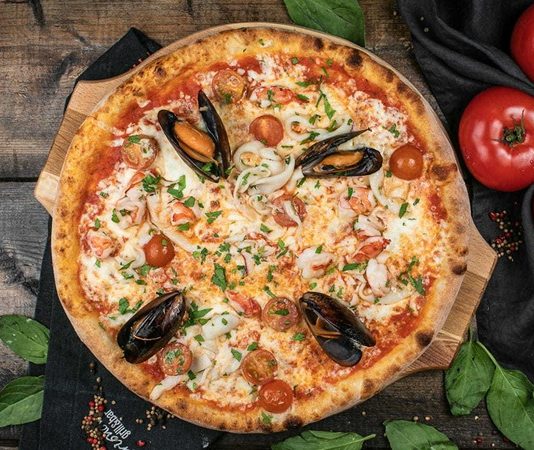 Deniz mahsullü pizza, klasik İtalyan pizzalarının deniz ürünleriyle zenginleştirilmiş modern bir yorumudur. Akdeniz ve İtalyan mutfağından ilham alan bu pizza, dünya genelinde kısa sürede popülerlik kazanmıştır. Özellikle taze deniz ürünleri ve kaliteli malzemelerin birleşimi, pizzayı hem lezzet hem de görsellik açısından özel kılar. Konulu bir haber görseli.