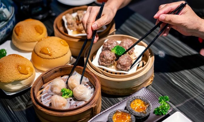 Dim Sum Lezzetinin Küresel Yolculuğu ve Popülerliği Dim Sum, Çin mutfağının en köklü ve sevilen geleneklerinden biridir. Çay kültürüyle özdeşleşen bu yemek türü, küçük porsiyonlar halinde servis edilen çeşitli yiyeceklerden oluşur. Tarihi, yüzyıllar öncesine dayanan bu lezzet, özellikle Guangdong bölgesinde ortaya çıkmış ve zamanla Çin’in farklı bölgelerine yayılmıştır. Yolculara hızlı ve doyurucu yiyecek sunma amacıyla başlayan bu gelenek, bugün hem Çin mutfağının hem de dünya gastronomisinin vazgeçilmez bir parçası haline gelmiştir. Konulu bir haber görseli.