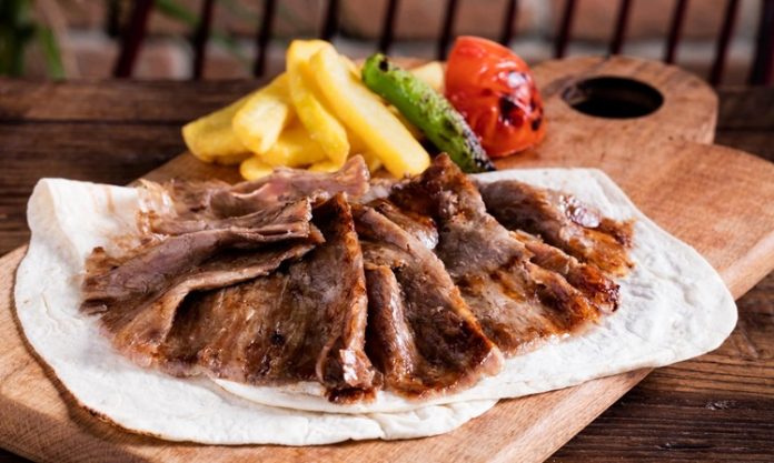 Et Döner Lezzetiyle Türk Mutfağının Vazgeçilmez Lezzeti Türk mutfağının en önemli lezzetlerinden biri olan et döner, tarihsel olarak Osmanlı döneminden günümüze kadar uzanan bir yolculuğa sahiptir. Yatay şişlerde pişirilen etlerin zamanla dikey şişlere geçirilmesiyle ortaya çıkan bu yöntem, özellikle hızlı servis imkânı ve eşsiz lezzetiyle kısa sürede halkın gözdesi haline gelmiştir. Dönerin geçmişi, yalnızca bir yemeğin tarihi değil, aynı zamanda Anadolu’nun kültürel çeşitliliğinin de bir yansımasıdır. Konulu bir haber görseli.