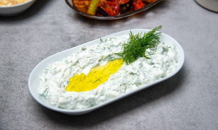 Haydari İle Sofralara Ferahlık Katın Haydari, özellikle kahvaltı sofralarının ve mezelerin vazgeçilmez tatlarından biridir. Yoğurt bazlı bu lezzetli meze, hem hafif hem de besleyici olmasıyla öne çıkar. Haydari, yüksek protein içeriği sayesinde kas ve kemik sağlığını desteklerken, probiyotik özelliği ile sindirim sistemine katkıda bulunur. İçerdiği sarımsak ve dereotu gibi doğal malzemeler, lezzetin yanı sıra sağlık açısından da avantaj sağlar. Konulu bir haber görseli.