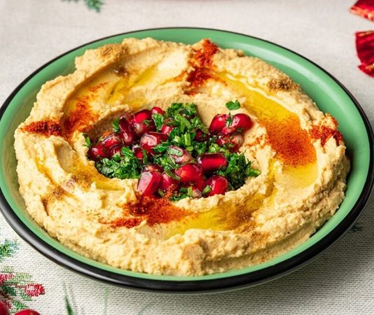 Humuslu Sandviç, geleneksel Ortadoğu lezzeti humusun taze ekmek veya lavaş arasına konularak hazırlandığı pratik bir öğün seçeneğidir. Protein ve lif açısından zengin olan humus, nohut bazlı yapısı sayesinde doyurucu ve besleyici bir alternatiftir. Sandviçlerin içine domates, salatalık, marul, biber ve çeşitli yeşillikler eklenerek vitamin değerleri artırılır. Konulu bir haber görseli.