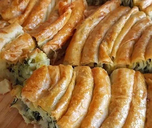 Ispanaklı Börek: Geleneksel Lezzetin Modern Sunumu Ispanaklı börek, hem kahvaltı sofralarının hem de özel davetlerin vazgeçilmez lezzetlerinden biridir. İncecik açılmış yufkaların arasında yer alan ıspanak, böreğe hem doğal bir renk hem de zengin bir besin değeri katar. Ispanaklı börek, özellikle ev yapımı olduğunda, hem lezzet hem de sağlık açısından sofralara değer katar. Bu yazımızda ıspanaklı böreğin tarihçesinden malzeme seçimlerine, hazırlık aşamalarından pişirme tekniklerine kadar detaylı bilgiler bulabilirsiniz. Konulu bir haber görseli.