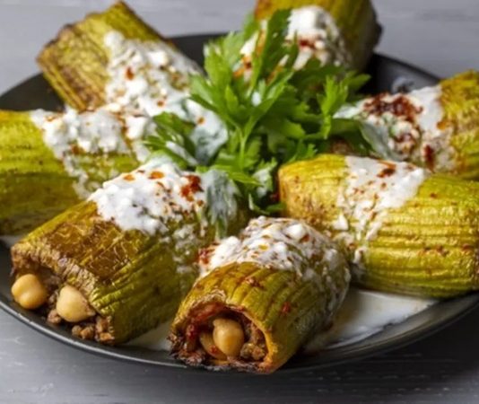 Türk mutfağının vazgeçilmezlerinden biri olan kabak dolması, hafifliği ve besleyici özelliğiyle yüzyıllardır sofralarda kendine özel bir yer edinmiştir. Anadolu’nun bereketli topraklarında yetişen taze kabaklarla hazırlanan bu yemek, hem günlük öğünlerde hem de özel davetlerde tercih edilen lezzetler arasında bulunur. Dolma kültürünün önemli temsilcilerinden biri olan kabak dolması, sağlıklı ve doyurucu yönüyle her yaştan insanın ilgisini çeker. Konulu bir haber görseli.