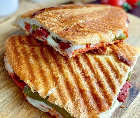 Karışık tost, özellikle Türkiye’de sabah kahvaltılarının ve ara öğünlerin vazgeçilmez lezzetlerinden biri haline gelmiştir. Bu tost çeşidi, klasik kaşarlı tostun ötesine geçerek sucuk, salam, domates, biber ve peynir gibi malzemelerin bir araya gelmesiyle hazırlanır. Böylece hem doyurucu hem de zengin bir lezzet sunar. Konulu bir haber görseli.