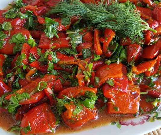 Közlenmiş Biber Salatası: Sofraların Vazgeçilmez Lezzeti Közlenmiş biber salatası, Türk mutfağının klasik mezelerinden biri olarak bilinir ve sofraların renkli sunumları arasında yer alır. Bu salata, özellikle yaz ve kış sofralarında, hem pratik hem de lezzetli bir başlangıç olarak tercih edilir. Közleme yöntemi, biberlerin aromasını yoğunlaştırır ve salataya karakteristik bir tat katar. Konulu bir haber görseli.