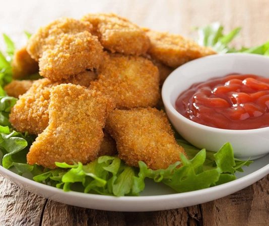 Nugget, özellikle hızlı ve pratik öğün arayanların favori seçeneklerinden biri haline gelmiş bir yiyecektir. Kökeni Amerika’ya dayanan bu atıştırmalık, 1950’li yıllarda geliştirilmiş ve kısa sürede dünya çapında popüler olmuştur. Tavuk eti, kaplamalı ve kızartılmış olarak hazırlanarak altın sarısı bir dış yüzeye kavuşur. Konulu bir haber görseli.