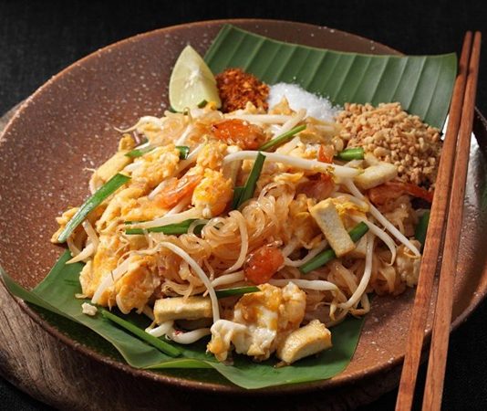 Pad Thai, Tayland mutfağının en bilinen yemeklerinden biridir ve dünya genelinde milyonlarca insan tarafından sevilerek tüketilmektedir. Bu yemek, özellikle Tayland’ın kimliğini yansıtan bir lezzet olarak öne çıkar. 1930’lu yıllarda ülkenin milli kimliğini güçlendirmek amacıyla öne çıkarılan bu yemek, kısa sürede Tayland’ın ulusal yemeklerinden biri haline gelmiştir. Pirinç eriştesiyle yapılan bu özel yemek, Tayland’ın zengin mutfak kültürünü uluslararası alanda temsil etmektedir. Konulu bir haber görseli.
