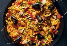 Paella, İspanya’nın en bilinen yemeklerinden biri olarak dünya mutfağında önemli bir yere sahiptir. Özellikle Valencia bölgesinde ortaya çıkan bu yemek, zamanla tüm ülkeye ve oradan da dünyaya yayılmıştır. Tarihi 15. yüzyıla kadar uzanan paella, köylülerin tarlalarda buldukları malzemeleri bir araya getirerek pişirdikleri pratik bir yemek olarak doğmuştur. Konulu bir haber görseli.