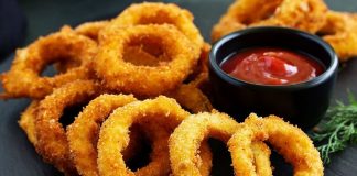 Soğan halkası, fast food kültürünün en sevilen atıştırmalıklarından biri olarak öne çıkıyor. Tarihi 20. yüzyılın ortalarına dayanan bu lezzet, özellikle Amerika’da popülerlik kazanmış ve kısa sürede dünya mutfaklarına yayılmıştır. Patates kızartmaları ve burgerlerin yanında ikincil lezzet olarak sunulan soğan halkaları, hem çıtır dokusu hem de tatlımsı soğan aroması ile dikkat çekiyor. Konulu bir haber görseli.