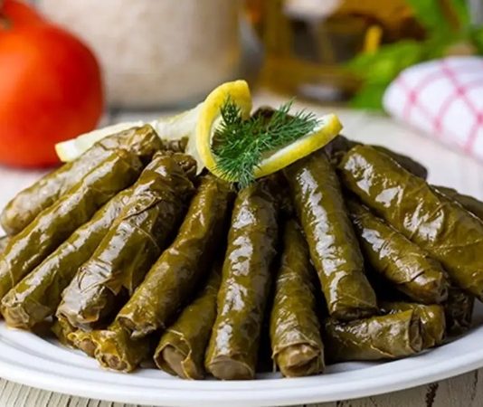 Türk mutfağının en köklü lezzetlerinden biri olan yaprak sarma, tarih boyunca hem sofraları hem de kültürü zenginleştiren bir yemek olarak bilinir. Osmanlı döneminden günümüze uzanan bu gelenek, özellikle özel günlerde ve davet sofralarında kendine yer bulur. Yaprak sarmanın hazırlanışı ve sunumu, mutfak kültürümüzün inceliklerini gösterir ve aile bağlarını güçlendiren bir unsur olarak öne çıkar. Konulu bir haber görseli.