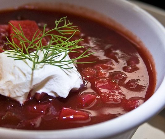 Doğu Avrupa mutfağının en ikonik çorbalarından biri olan Borscht, son yıllarda gastronomi dünyasında yeniden popülerleşiyor. Özellikle kırmızı pancarın yoğun rengini ve tatlı-ekşi aromalarını bir araya getiren bu çorba, hem geleneksel sofraların hem de modern restoran menülerinin vazgeçilmez bir parçası hâline geldi. Besleyici içeriği ve doyurucu yapısıyla bilinen Borscht, sadece Doğu Avrupa’da değil, dünya çapında da tanınan bir lezzet olarak öne çıkıyor. Türkiye’de de son yıllarda artan gastronomi ilgisi sayesinde bu çorba mutfaklarda yerini almış durumda. Konulu bir haber görseli.