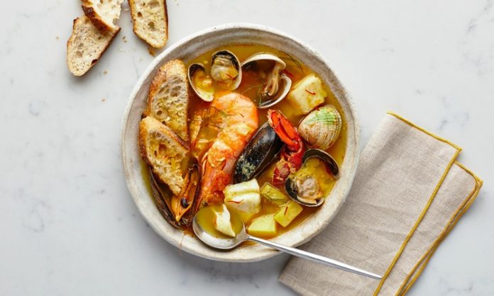 Bouillabaisse Akdeniz’in En Ünlü Balık Çorbası Yeniden Dünya Sahnesinde Fransa’nın güney sahillerinde doğan Bouillabaisse, yüzyıllardır Akdeniz mutfak kültürünün en önemli simgelerinden biri olarak biliniyor. Marsilya balıkçıları tarafından geliştirilen bu özel yemek, hem köklü tarihi hem de aromatik yapısıyla son yıllarda yeniden uluslararası arenada büyük bir popülerlik kazandı. Özellikle gastronomi dünyasında artan özgün tarif arayışı, Bouillabaisse gibi geleneksel lezzetleri yeniden öne çıkarıyor. Akdeniz’in karakteristik dokusunu yansıtan çorba, içerdiği taze balıklar, kabuklular ve aromatik sebzelerle hem besleyici hem de kültürel bir değer taşıyor. Konulu bir haber görseli.