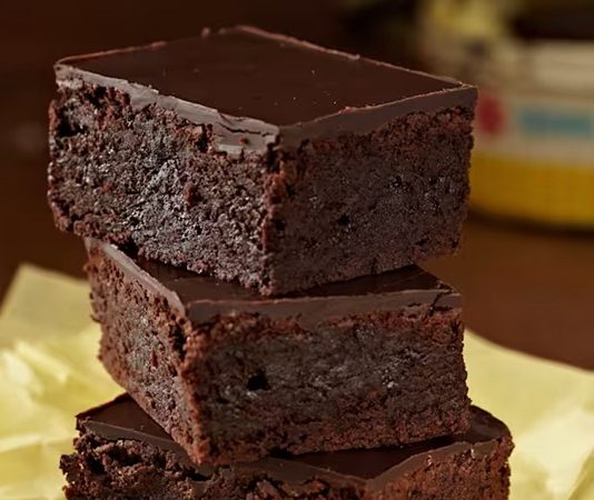 Brownie, yıllardır tatlı dünyasında popülerliğini koruyan, çikolatanın en yoğun halini sunan klasik bir hamur işi olarak biliniyor. Amerika’da doğan bu tatlı, bugün Türkiye’de de kahve menülerinin vazgeçilmezlerinden biri haline geldi. Hem evlerde hem kafelerde sıkça tercih edilen bu tatlının hikâyesi, aslında çikolatanın büyüleyici dünyasına olan ilginin bir yansıması. Son zamanlarda özellikle sosyal medya tariflerinin de yaygınlaşmasıyla birlikte, brownie yapımı ev mutfaklarında daha da popüler hale gelmiş durumda. Konulu bir haber görseli.