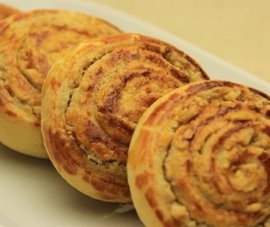 Türkiye’nin birçok bölgesinde uzun yıllardır hazırlanan Cevizli Çörek, son dönemde sosyal medyada yayılan yöresel tarif akımıyla birlikte yeniden gündeme geldi. Kahvaltı sofralarının vazgeçilmezi hâline gelen bu geleneksel hamur işi, özellikle ev yapımı lezzetlere olan ilginin artmasıyla daha fazla kişi tarafından keşfedilmeye başladı. Gerek dokusu gerekse cevizli iç harcının aromasıyla dikkat çeken Cevizli Çörek, son aylarda fırınlar, pastaneler ve ev mutfaklarında en çok tercih edilen ürünlerden biri oldu. Gastronomi yazarları ise bu yükselişi, “köklü tariflerin dönüşü” olarak değerlendiriyor. Konulu bir haber görseli.