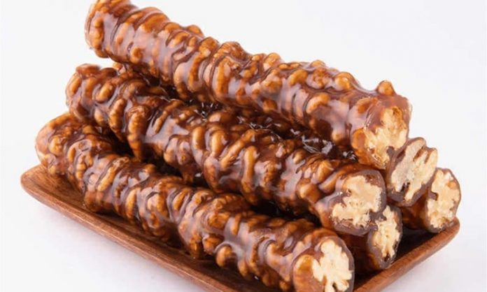 Anadolu mutfağının en sevilen geleneksel tatlarından biri olan cevizli sucuk, özellikle kış aylarının yaklaşmasıyla yeniden gündemde. Doğal içeriği, uzun süre saklanabilmesi ve hem atıştırmalık hem de enerji verici bir yiyecek olarak tüketilmesi, onu her yıl olduğu gibi bu yıl da yoğun ilgi gören bir ürün hâline getiriyor. Üzüm şırasının yoğunlaştırılmasıyla elde edilen karışımın ceviz dizilmiş ipe özenle geçirilip kat kat işlenmesi, bu tatlıyı sadece bir yiyecek olmaktan çıkarıp kültürel bir mirasa dönüştürüyor. Son dönemde yerel üreticilerin doğal yöntemlere dönüş yapmasıyla birlikte cevizli sucuk hem şehir pazarlarında hem de online satışlarda gittikçe daha görünür hâle geliyor. Konulu bir haber görseli.