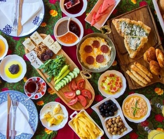 Türk kültüründe evlilik süreci yalnızca iki insanın hayatını birleştirmesi değil, aynı zamanda ailelerin ve çevrenin ortaklaştığı geniş bir toplumsal ritüeldir. Bu sürecin en zarif ve samimi adımlarından biri olan Çeyiz Kahvaltısı, hem paylaşım hem de tanışma odaklı bir gelenek olarak dikkat çeker. Gösterişten uzak ama anlam yüklü bu sofralar, evlilik hazırlıklarının duygusal yönünü ön plana çıkarır. Konulu bir haber görseli.