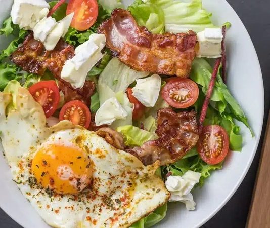 Ketojenik beslenme son yıllarda yalnızca kilo vermeye odaklanan geçici diyetlerden biri olarak değil, bütüncül bir yaşam tarzı olarak öne çıkıyor. Özellikle ketojenik yemek kavramı, karbonhidrat merkezli klasik beslenme alışkanlıklarını sorgulayan bireyler için güçlü bir alternatif oluşturuyor. Yağ oranı yüksek, karbonhidrat oranı oldukça düşük olan bu beslenme düzeni; metabolizmanın çalışma biçimini değiştirmesiyle dikkat çekiyor. Bu yönüyle ketojenik mutfak, hem fiziksel hem de zihinsel performansla ilişkilendirilen bir beslenme anlayışına dönüşmüş durumda. Konulu bir haber görseli.