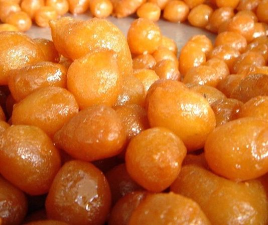 Türk mutfağının en köklü tatlılarından biri olan lokma, yüzyıllardır hem Anadolu’nun hem de Ege’nin kültürel mirasını taşımaya devam eden özel bir lezzet olarak öne çıkıyor. Özellikle paylaşma, bereket ve toplumsal dayanışmayı temsil eden bu tatlı, günümüzde sadece geleneksel törenlerde değil, modern gastronomi alanında da sıkça tercih edilen bir tat haline geldi. Hafif kabaran hamurunun kızgın yağda altın rengi alması ve ardından şerbetle buluşması, lokmayı eşsiz kılan temel özelliklerden biri. Sokak tezgâhlarının değişmeyen yüzü olan lokma, bugün artık restoranlarda ve kafelerde de farklı sunumlarla yer buluyor. Konulu bir haber görseli.