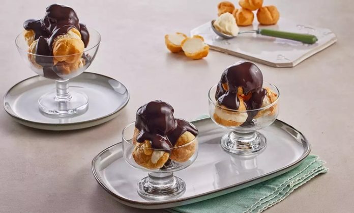 Profiterol Tatlı Dünyasında Zarif Bir Klasiğe Dönüşüyor Fransız mutfağının en seçkin tatlılarından biri olan profiterol, uzun yıllardır hem restoranların hem de ev mutfaklarının en sevilen lezzetlerinden biri olarak yerini koruyor. Çıtır hamurun içindeki hafif krema ve üzerine dökülen yoğun çikolata sosuyla oldukça cezbedici bir tat sunan profiterol, özellikle misafir ağırlamalarında şık bir sunum oluşturmasıyla ön plana çıkıyor. Günümüzde pastane vitrinlerinde sıkça görülen bu tatlı, son dönemde ev yapımı tariflerin popülerleşmesiyle birlikte mutfakta daha da yaygın şekilde hazırlanıyor. Konulu bir haber görseli.