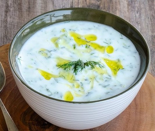 Soğuk Yoğurtlu Kabak Çorbası Yaz Sofralarının Ferahlatıcı Lezzeti Soğuk yoğurtlu kabak çorbası, özellikle yaz aylarında sofraların vazgeçilmez başlangıcı olarak öne çıkıyor. Hafif ve ferahlatıcı bir tarif olan bu çorba, hem besleyici hem de pratik oluşuyla mutfakların favorisi hâline geliyor. Soğuk yoğurtlu kabak çorbası, taze kabak ve yoğurt ile hazırlanırken içerisine eklenen dereotu ve baharatlar çorbanın lezzetini artırıyor. Yaz sofralarında hem aile yemeklerinde hem de davet sofralarında tercih edilen bir seçenek olarak dikkat çekiyor. Konulu bir haber görseli.