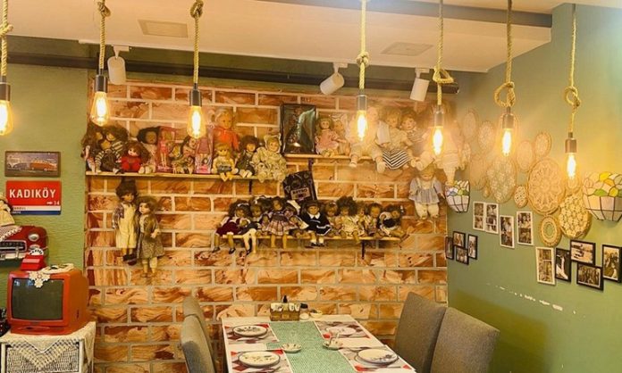Geçmişin İzlerini Taşıyan Nostaljik Kafeler Şehirlerde Yeniden Canlanıyor Modern şehir hayatının hızlı temposu içinde insanlar, geçmişe dair sıcak duygular uyandıran mekânlara her zamankinden daha fazla ilgi göstermeye başladı. Bu ilginin merkezinde ise nostaljik kafeler yer alıyor. Eski eşyalarla dekore edilmiş, geçmiş yılların müziklerini yaşatan ve samimi atmosferiyle öne çıkan bu kafeler, ziyaretçilerine yalnızca bir içecek değil, aynı zamanda bir zaman yolculuğu sunuyor. Nostaljik kafeler, anıları tazeleyen yapısıyla şehir yaşamında özel bir konuma sahip. Konulu bir haber görseli.